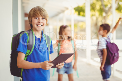 Schoolboy holding digital tablet in school corridor