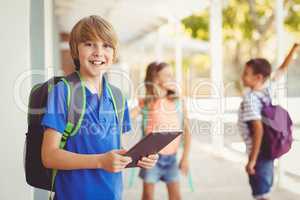 Schoolboy holding digital tablet in school corridor