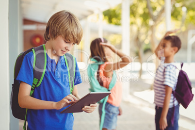 Schoolboy using digital tablet in school corridor