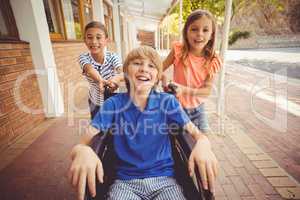 School kids pushing a boy on wheelchair