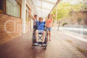 School kids pushing a boy on wheelchair