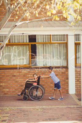 Schoolboy pushing a girl on wheelchair