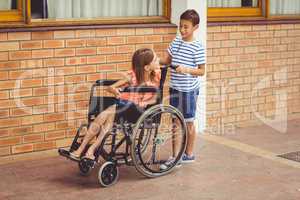 Schoolboy talking to a girl on wheelchair