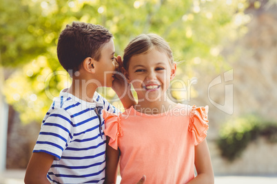 Happy boy whispering a secret in girls ear