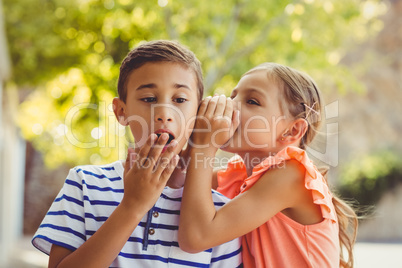 Girl whispering a secret in boys ear