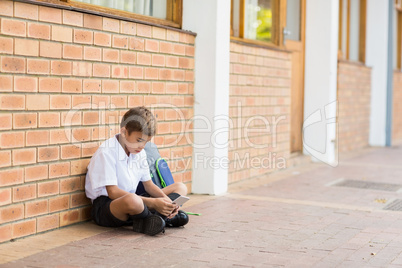 Schoolboy sitting in corridor and using mobile phone