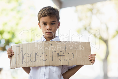 Schoolboy holding placard which reads please help