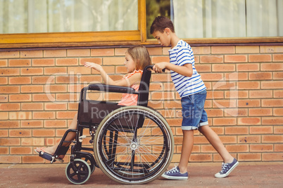 Schoolboy pushing a girl on wheelchair