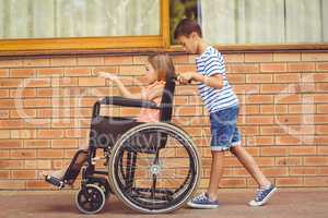 Schoolboy pushing a girl on wheelchair