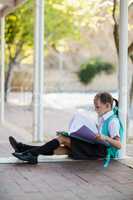 Schoolgirl sitting in corridor and reading books