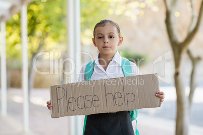 Schoolgirl holding placard which reads please help