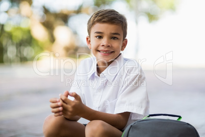 Happy school boy sitting in campus