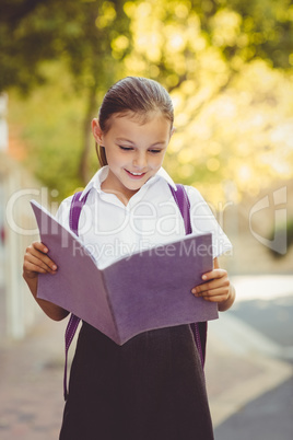 Happy schoolgirl reading book in campus