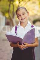 Happy schoolgirl reading book in campus