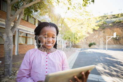 Happy school girl using digital tablet in campus