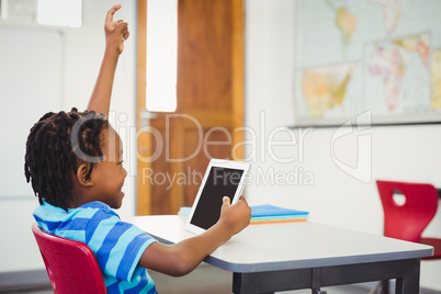 Happy schoolboy using digital tablet in classroom