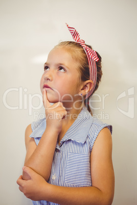 Thoughtful cute girl with hand on chin in classroom