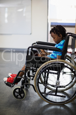 Schoolboy sitting on wheelchair and using digital tablet