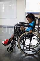 Schoolboy sitting on wheelchair and using digital tablet