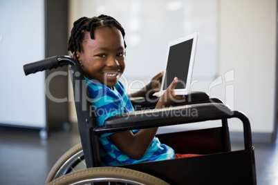 Schoolboy sitting on wheelchair and using digital tablet