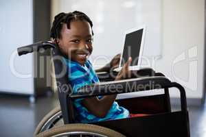 Schoolboy sitting on wheelchair and using digital tablet