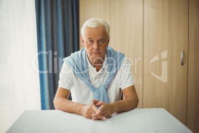 Sad senior man sitting at table
