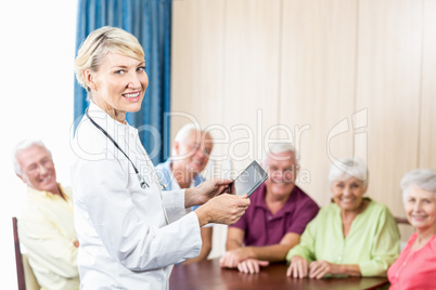 Smiling seniors and nurse holding a tablet