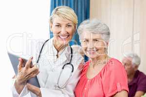 Smiling senior woman and nurse holding a tablet