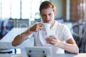 Man using mobile phone while having cup of coffee