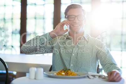 Happy man talking on mobile phone while having a lunch