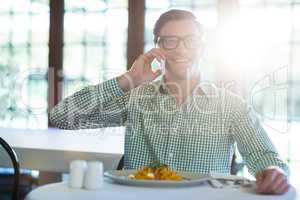 Happy man talking on mobile phone while having a lunch