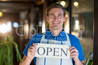 Portrait of smiling chef holding open sign