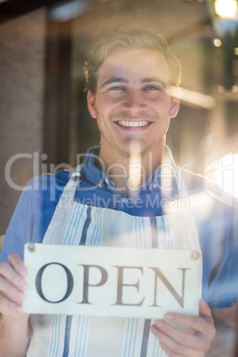 Portrait of smiling chef holding open sign