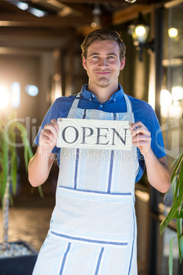 Portrait of smiling chef holding open sign