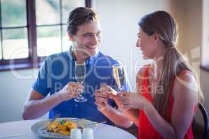 Happy young couple toasting champagne flutes while having lunch