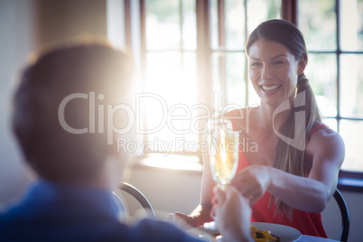 Happy young couple toasting champagne flutes while having lunch