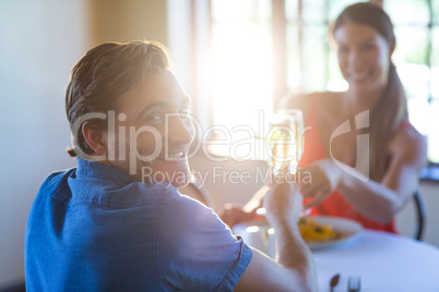 Portrait of young couple toasting champagne flutes while having lunch