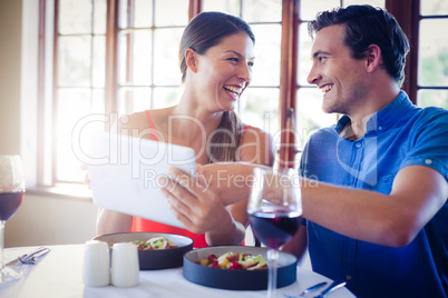 Happy couple using a digital tablet during lunch