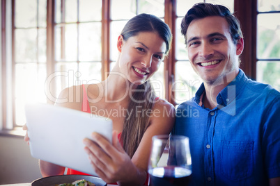 Portrait of happy couple using a digital tablet during lunch