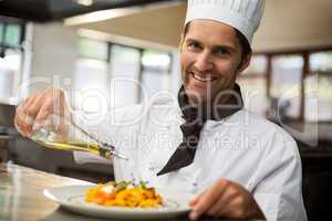 Portrait of happy chef pouring olive oil on meal