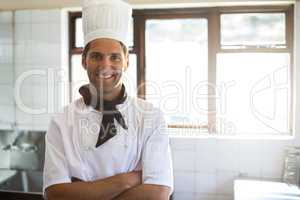 Portrait of smiling chef standing with arms crossed