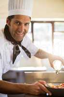 Portrait of happy chef pouring olive oil on salad