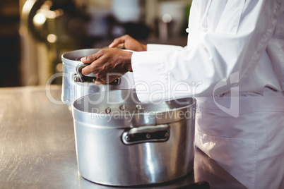 Mid section of chef holding cooking pot