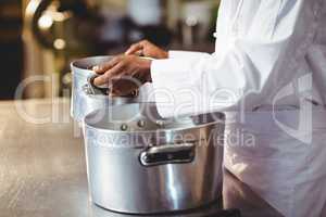 Mid section of chef holding cooking pot