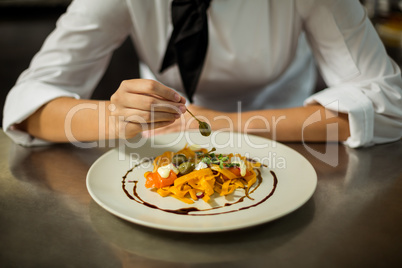 Mid section of chef garnishing pasta dish with olive