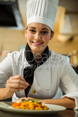 Happy head chef garnishing pasta dish with olive