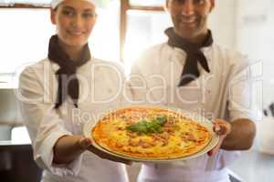 Portrait of two chef presenting a pizza