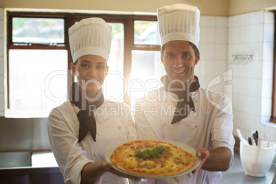 Portrait of two chef presenting a pizza