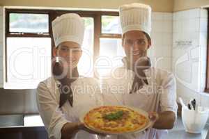 Portrait of two chef presenting a pizza