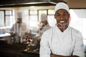 Portrait of smiling chef standing with arms crossed